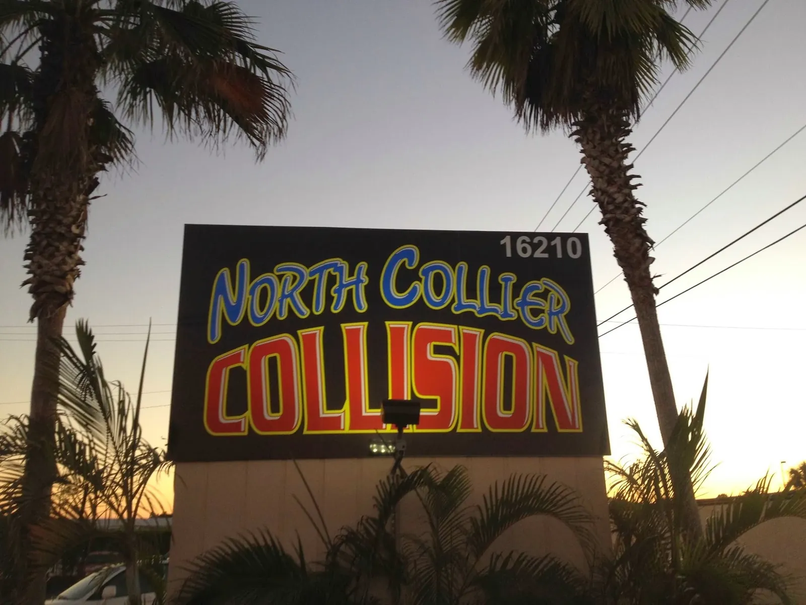 The North Collier Collision sign at 16210 Old 41 at dusk, between two palm trees